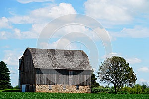 An old wooden abandoned farm barn sits on a farm field outside of Fond du Lac, Wisconsin.