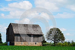 An old wooden abandoned farm barn sits on a farm field outside of Fond du Lac, Wisconsin.