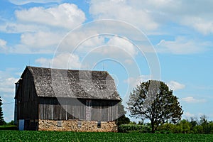 An old wooden abandoned farm barn sits on a farm field outside of Fond du Lac, Wisconsin.