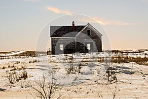 Old wooden abandoned house with snow on the ground.