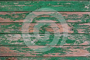 Old wooden background consisting of frayed textured boards, painted with green paint, which peeled off.