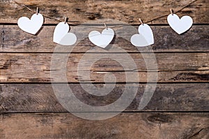 Old wooden background with a garland of white hearts. Natural rope and clothespins. Concept of recognition of love, romantic