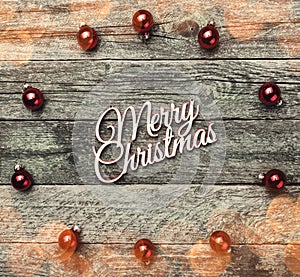 Old wooden background. With red balls, Merry Christmas text in the center, top view