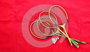 Old wooden badminton rackets and shuttlecock on red background