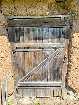 Old wooden barn door on a clay house