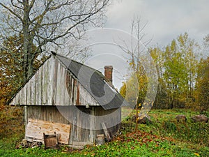 Old wooden barn by a forest. Country side. Cloudy sky. Small farm building of warehouse.