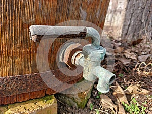 Old wooden barrel, rusty iron hoop, copper tap outdoors in sunlight