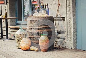 Old wooden barrels on which there are pumpkins and bottles.