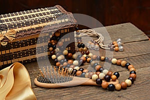 Old wooden beads, wooden casket and hairbrush on table