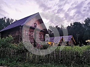 An old wooden Belarusian hut on a farm in the evening, cloudy sky