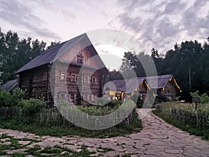 An old wooden Belarusian hut on a farm in the evening, cloudy sky