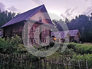 An old wooden Belarusian hut on a farm in the evening, cloudy sky