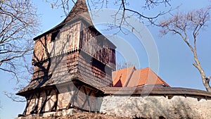 Stará dřevěná zvonice u opevněného kostela.