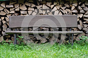 Old wooden bench on a background of a stack of logs