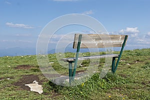 Old wooden bench on peak of summer green mountains,