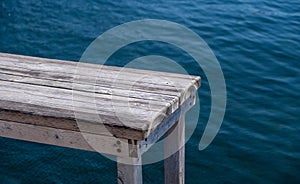 Old wooden bench, pier over blue sea background