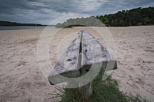 Old wooden bench on sand river bank at cloudy sunset