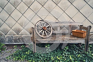 Old wooden bench with a wooden wagon wheel and a flower pot