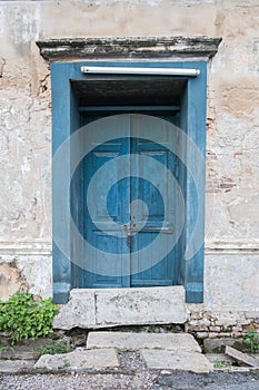 Old wooden blue door in the wall of old building.