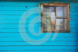 Old wooden blue house or barn with a barred small window