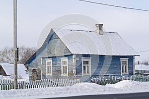 Old wooden blue house in village. Farmhouse in Belarus. View of rustic ethnic house, rural landscape in winter day