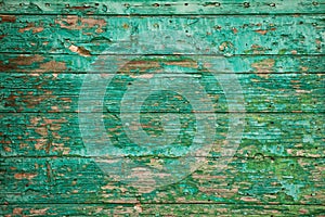 Old wooden board with peeling paint. Background of green flaky paint on cracked plank of wood