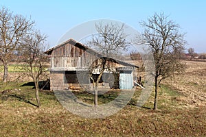 Old wooden boards storage shed with attached barn and improvised dog kennel