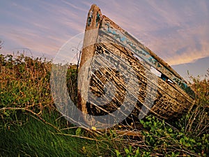 Old wooden boat ashore in a field.