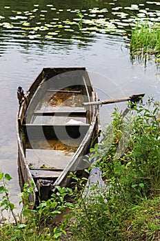 Old wooden boat on the coast of the forest river.