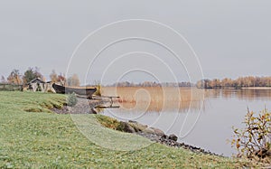 Old wooden boat and fishing net on the shore of beautiful misty lake and autumn forest landscape. Autumn forest and lake