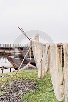 Old wooden boat and fishing net on the shore of beautiful misty lake and autumn forest landscape. Autumn forest and lake