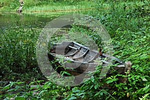 Old wooden boat in grass on the lake bank