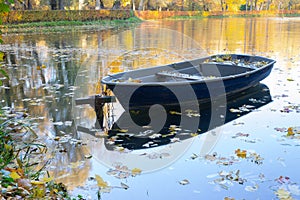 Old wooden boat on the lake bank in autumn season