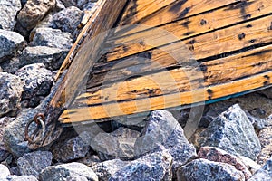 Old wooden boat lying on stones closeup