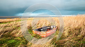 Old wooden boat in the reed next to the north sea on the Island Romo in Denmark, stormy weather in winter