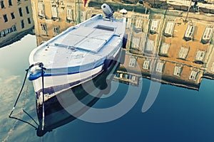 Old wooden boat, sky and ancient historical and building with reflection on blue water