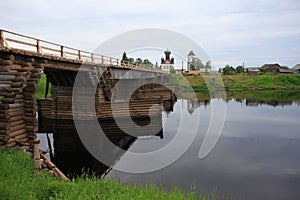 Old wooden bridge across the river. North Russia