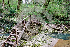 Old wooden bridge crossing the blue mountain stream