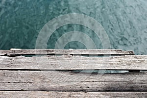 old wooden bridge by the lake with blue reflection in the water and mist.