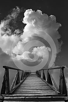 Old wooden bridge leads to unknown against sky and clouds