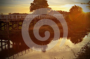 Old wooden bridge over river at sunset