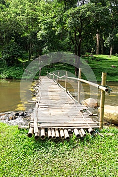 Old wooden bridge over the stream with green lawn