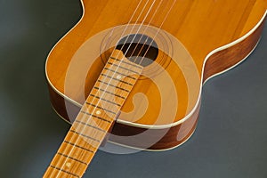 Old wooden brown guitar on a dark background