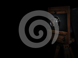Old wooden camera on a tripod  on black background