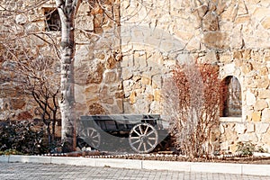 Old wooden cart against background of a strange stone wall of fortress