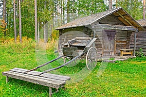 Old wooden cart in front of log barn
