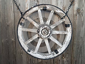 Old wooden cart wheel on a gray wooden wall