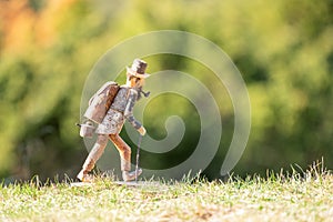 Old wooden carved out man hiker figure, with backpack, walking stick, tobacco pipe and hat outdoors in nature.