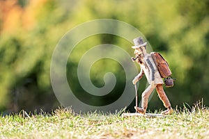 Old wooden carved out man hiker figure, with backpack, walking stick, tobacco pipe and hat outdoors in nature.