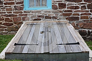 The old wooden cellar door is beneath the window.